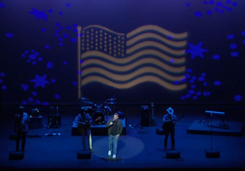 Cammo Voices performing with an American Flag projected behind them